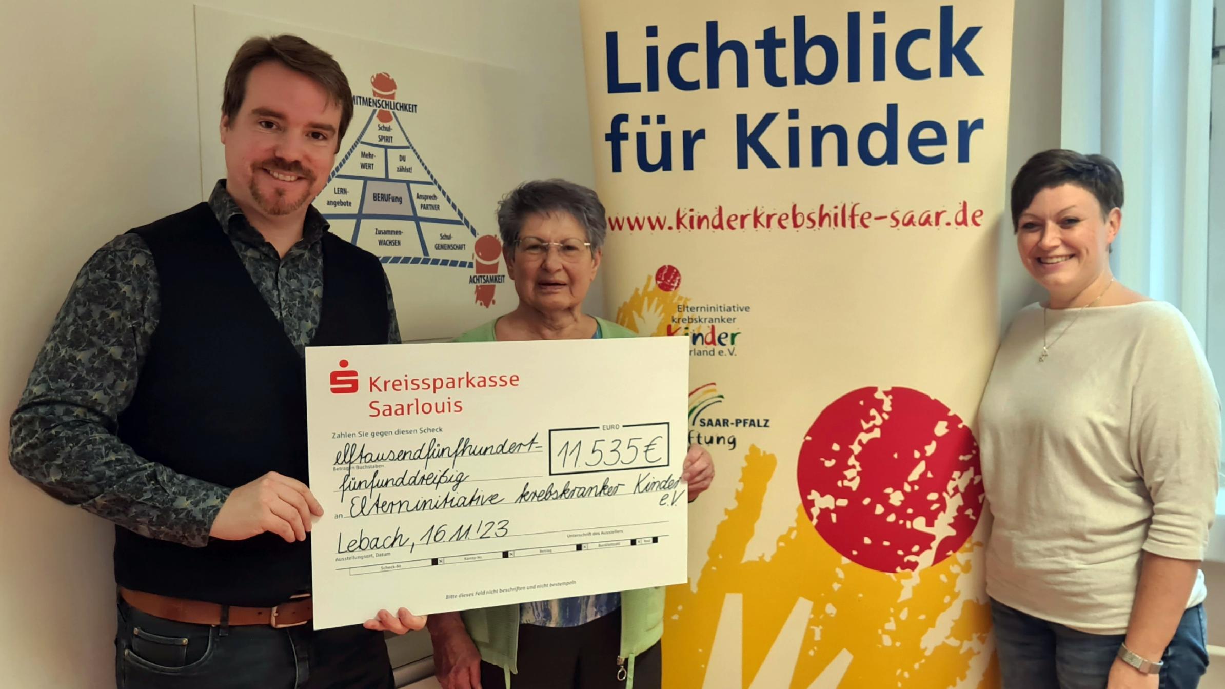 Die Schulleiter Andreas Hackert und Verena Laase überreichen den Spendenscheck an eine Vertreterin der Elterninitiative krebskranker Kinder e.V.