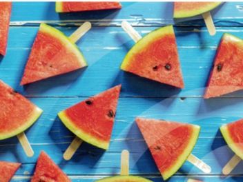 dreieckige Melonenstücke auf Stielen auf einem azurblauen Hintergrund